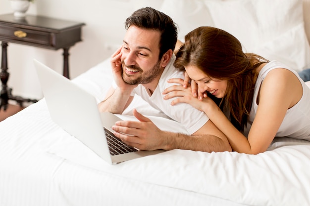 Pareja joven con portátil en la cama