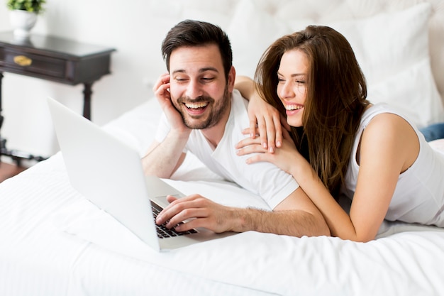 Pareja joven con portátil en la cama