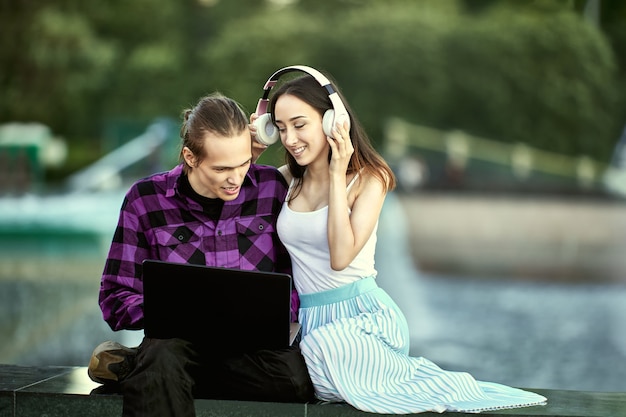 Pareja joven con portátil tiene cita al aire libre en verano