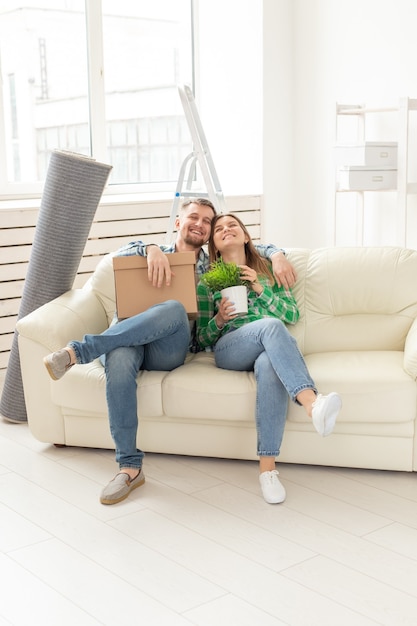 Pareja joven positiva en el amor marido y mujer están sentados en el sofá de la nueva sala de estar