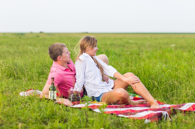 Pareja joven en la pradera de verano, hombre y mujer con picnic romántico.