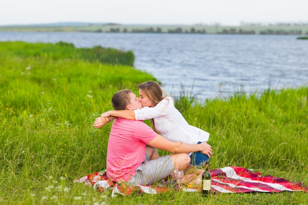 Pareja joven en la pradera de verano, hombre y mujer con picnic romántico.