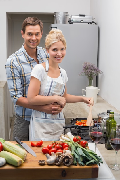 Pareja joven preparando comida juntos en la cocina