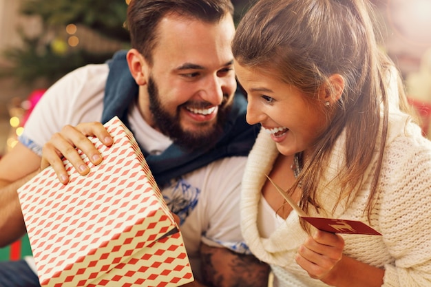 pareja joven, con, presente, encima, árbol de navidad