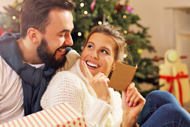 pareja joven, con, presente, encima, árbol de navidad