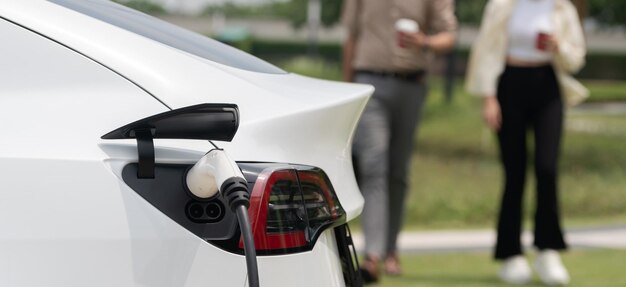 Foto una pareja joven puso un cargador para recargar la batería de un coche eléctrico.