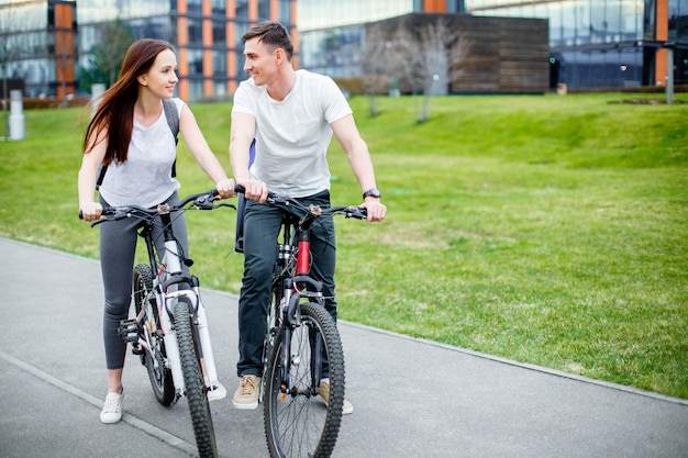 Pareja joven que va a dar un paseo en bicicleta en un día soleado en la ciudad