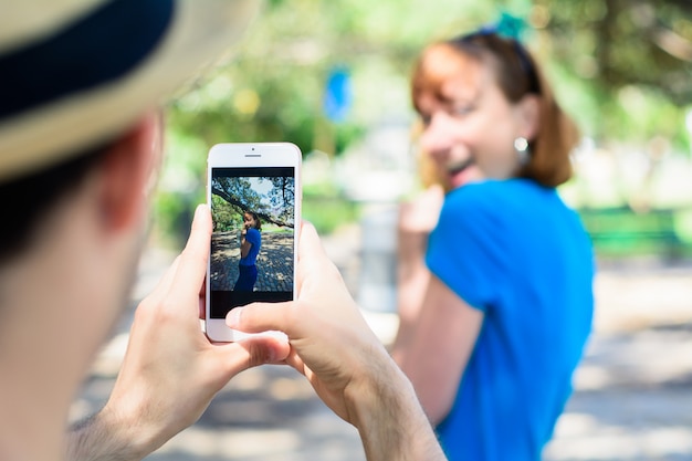 Foto pareja joven que toma la foto con la cámara del teléfono inteligente.