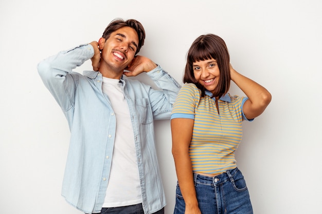 Pareja joven de raza mixta aislado sobre fondo blanco estirando los brazos, posición relajada.