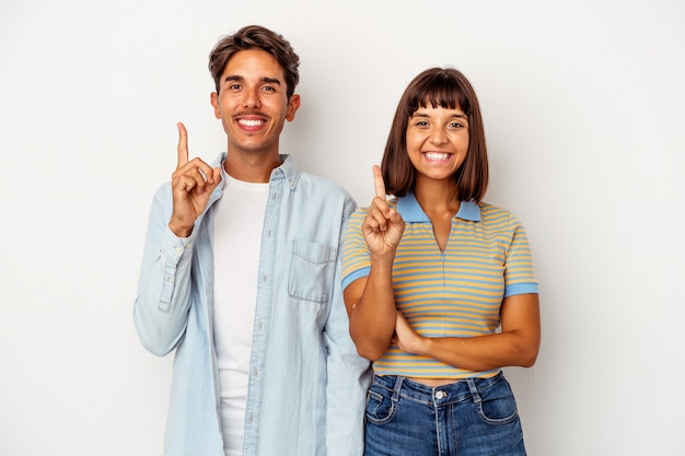 Foto pareja joven de raza mixta aislado sobre fondo blanco mostrando el número uno con el dedo.