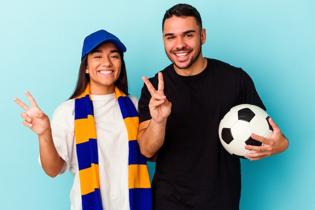 Pareja joven de raza mixta limpieza de casa aislado sobre fondo azul que muestra el número dos con los dedos.