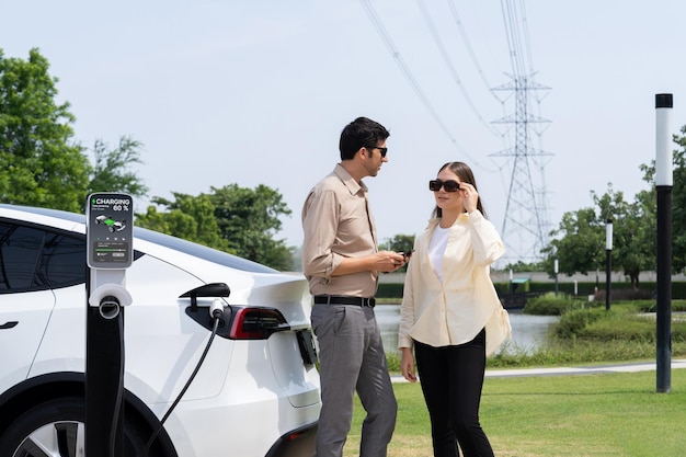 Una pareja joven recarga la batería de un automóvil eléctrico en una estación de carga