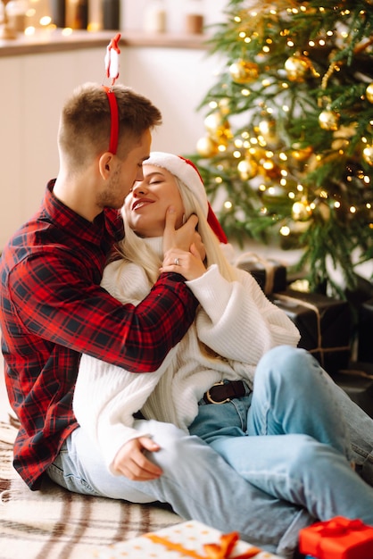 Pareja joven con regalos de Navidad en casa cerca del árbol de Navidad Día romántico Vacaciones Año Nuevo