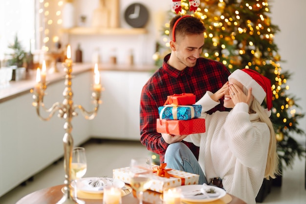 Pareja joven con regalos de Navidad en casa cerca del árbol de Navidad Día romántico Vacaciones Año Nuevo