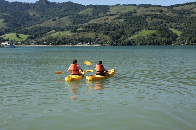 Pareja joven remando en kayak en el mar.