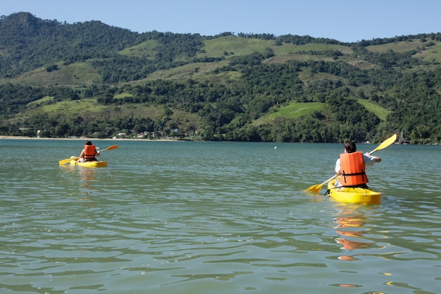 Pareja joven remando en kayak en el mar.