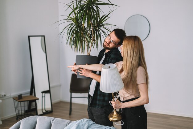 Pareja joven renovando su nueva casa y moviendo muebles juntos.