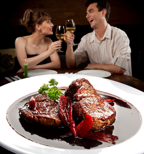 Foto pareja joven en el restaurante comiendo carne.