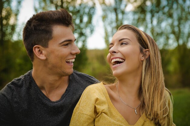 Foto una pareja joven riendo contra los árboles.