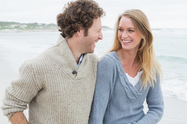 Pareja joven riendo en la playa