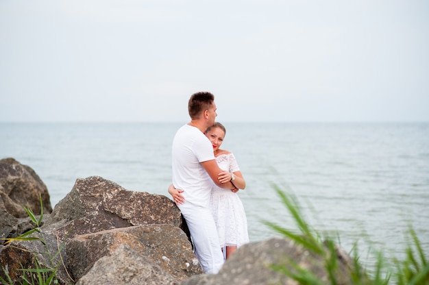 Pareja joven en las rocas en el mar