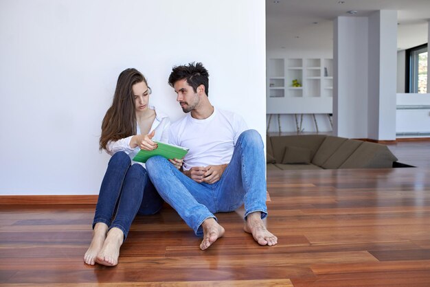 Una pareja joven romántica y relajada en una casa moderna usando una tableta