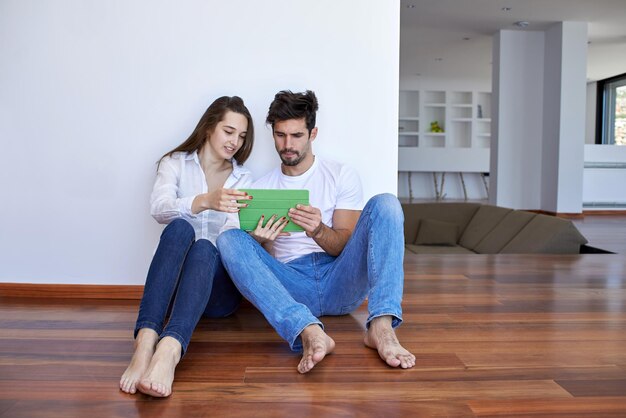 Una pareja joven romántica y relajada en una casa moderna usando una tableta