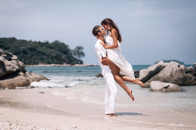 Pareja joven romantica en ropa blanca disfrutando de las vacaciones de verano en la playa Foto Premium