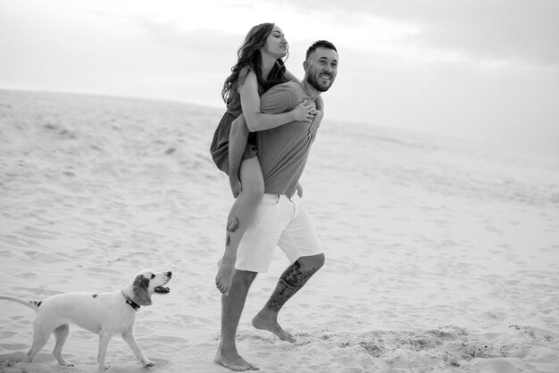 Pareja joven en ropa naranja con perro en las arenas blancas del desierto