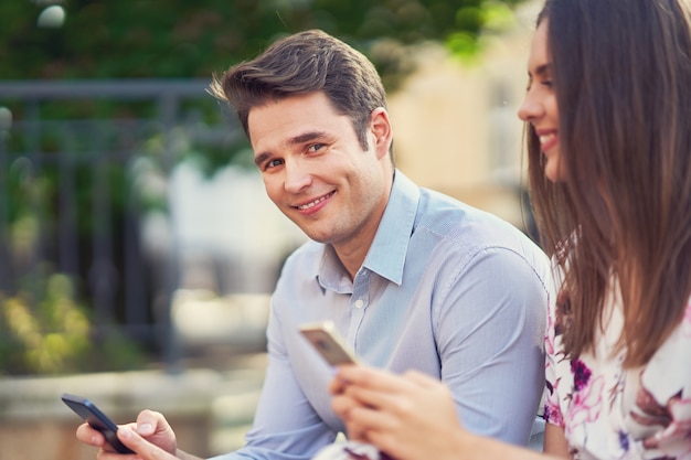 Pareja joven saliendo en el parque y usando teléfonos inteligentes