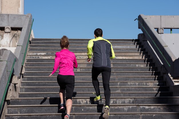 Una pareja joven y saludable trotando en escalones temprano en la mañana