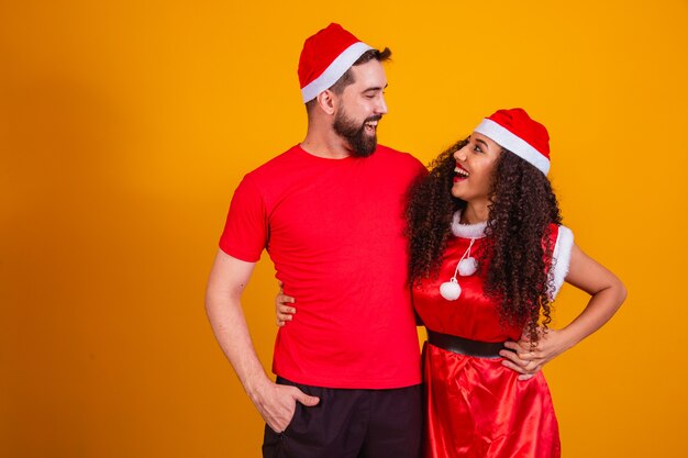 Pareja joven de San Valentín vestida para la noche de Navidad sobre fondo amarillo con espacio para texto.