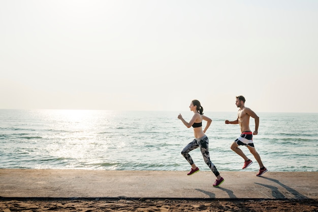 Pareja joven sana corriendo por la playa juntos