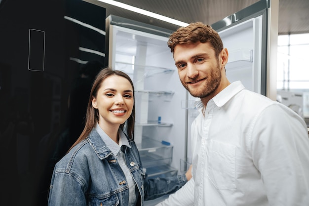 Pareja joven seleccionando refrigerador nuevo en la tienda de electrodomésticos