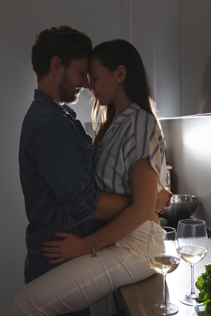 Foto pareja joven y sensual bebiendo vino y relajándose en casa