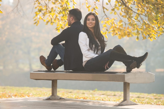 Pareja joven sentada en un banco en el hermoso día de otoño