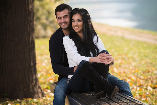 Pareja joven sentada en un banco en el hermoso día de otoño