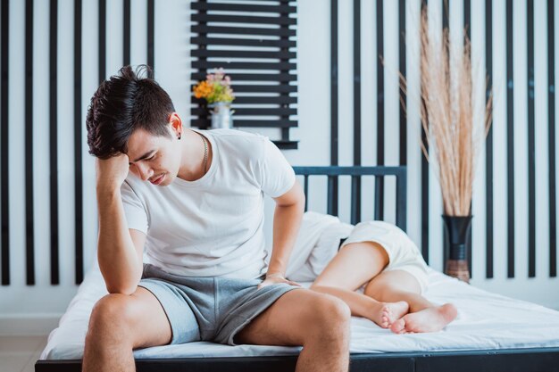 Foto una pareja joven sentada en la cama se siente aburrida en una relación