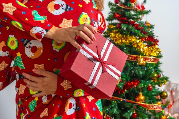 Una pareja joven sentada junto al árbol de Navidad, una novia muy feliz abrazando a un novio muy feliz