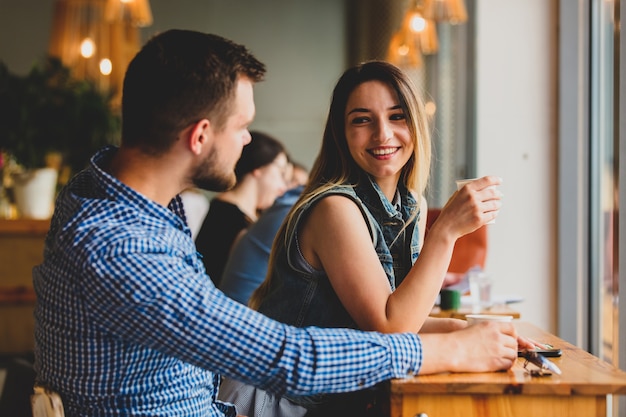 Pareja joven sentada en una mesa en un café y tomando café