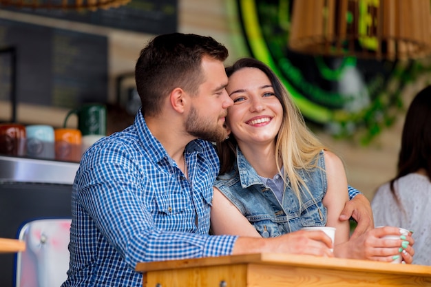 Pareja joven sentada en una mesa en un café y tomando café