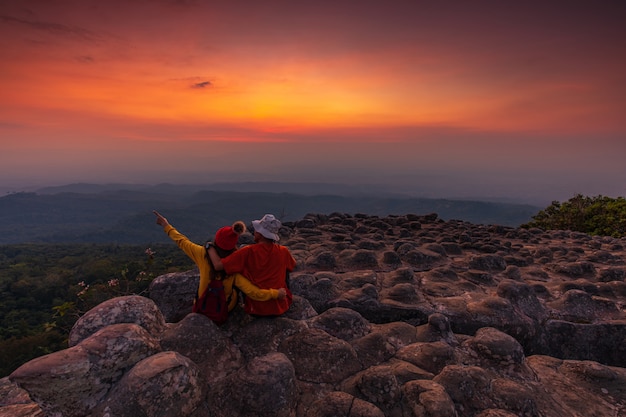 Foto pareja joven sentada en una roca en las montañas