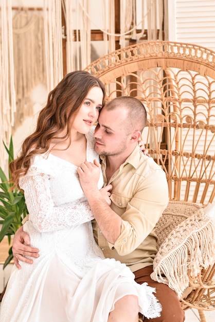 Pareja joven sentada en una silla de mimbre.