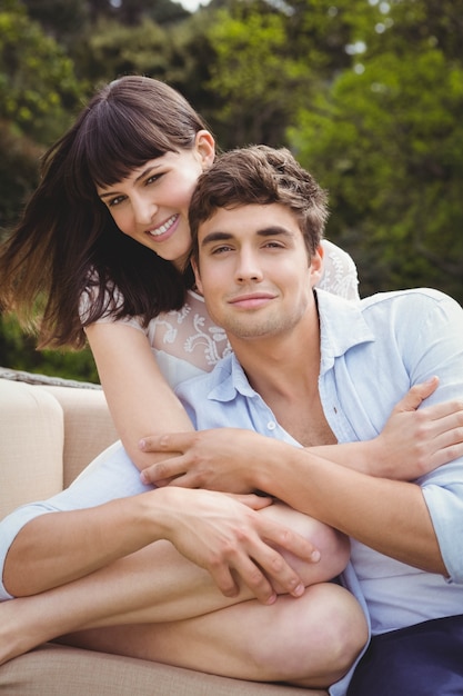 Pareja joven sentada en el sofá y abrazando al aire libre