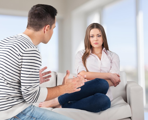 Pareja joven sentada en el sofá en casa.