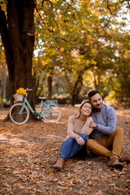 Pareja joven sentada en el suelo en el parque otoño