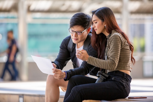 pareja joven, sentado, en, escalera, y, mirar papel, en, exterior