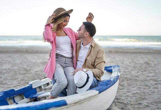 Una pareja joven se sienta junto a un viejo barco tradicional de pescadores