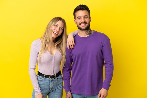 Pareja joven sobre fondo amarillo aislado feliz y riendo