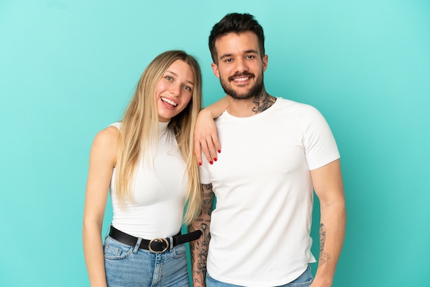 Pareja joven sobre fondo azul aislado feliz y riendo